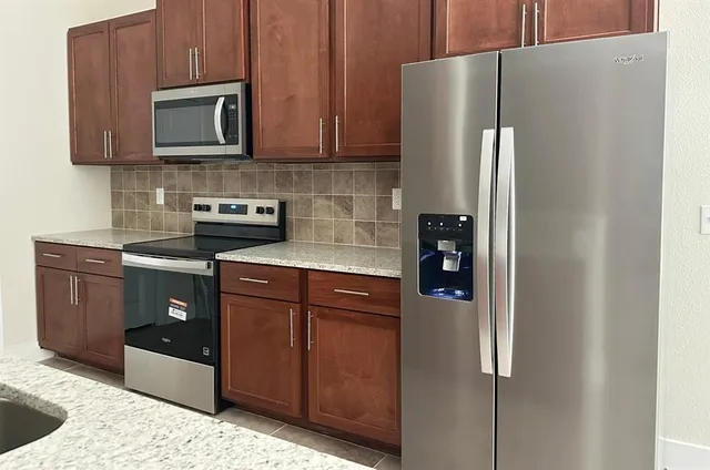 a kitchen with stainless steel appliances granite countertop a refrigerator and a stove top oven