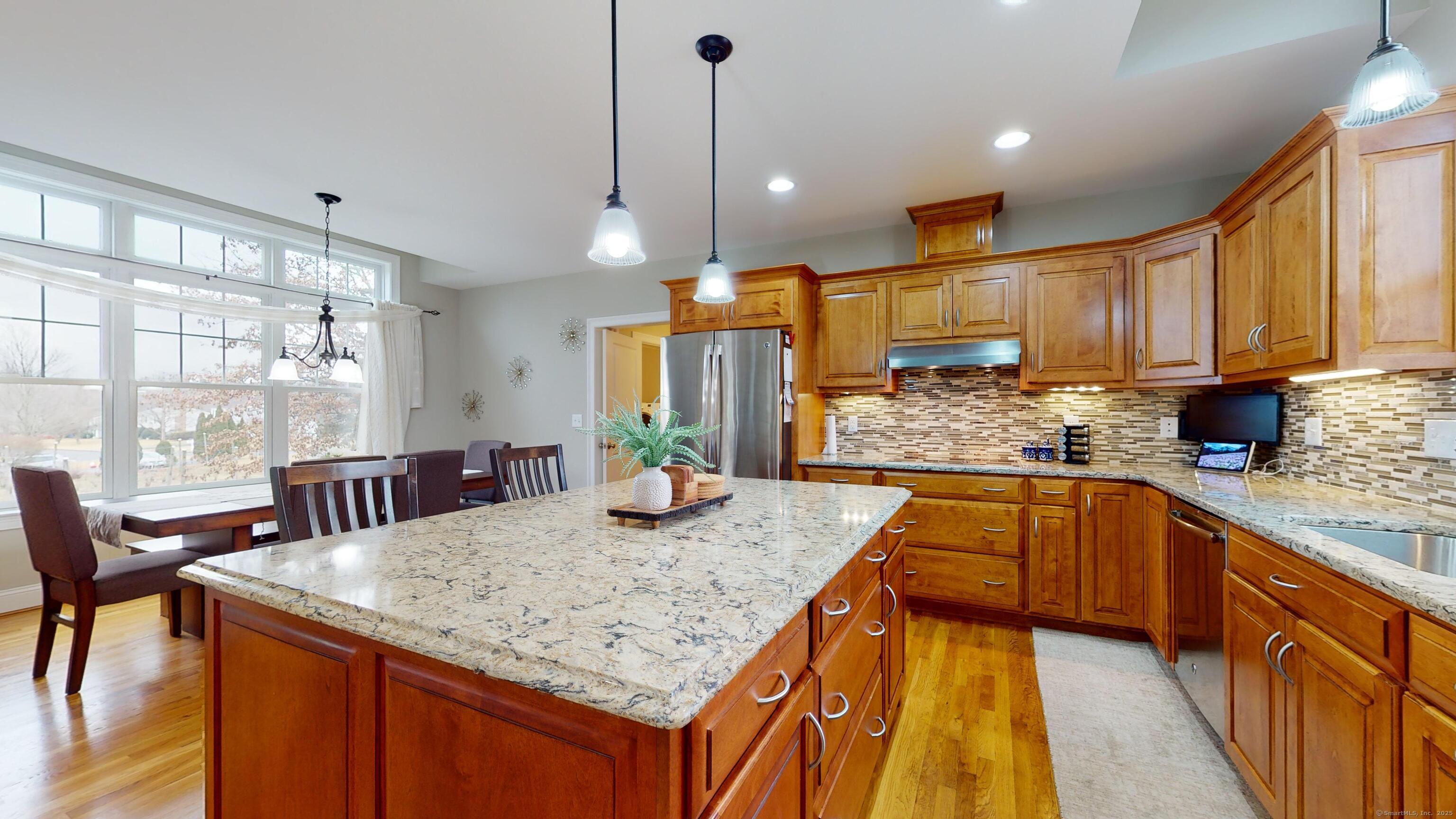 a kitchen with kitchen island granite countertop wooden cabinets a stove a sink with a dining table and chairs