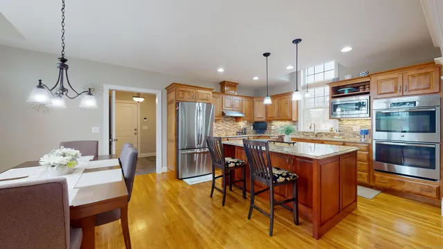 a kitchen with stainless steel appliances kitchen island granite countertop a table chairs and a refrigerator