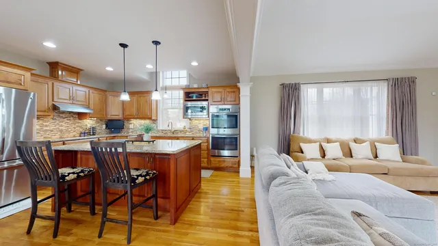 a living room with stainless steel appliances kitchen island granite countertop furniture and a large window