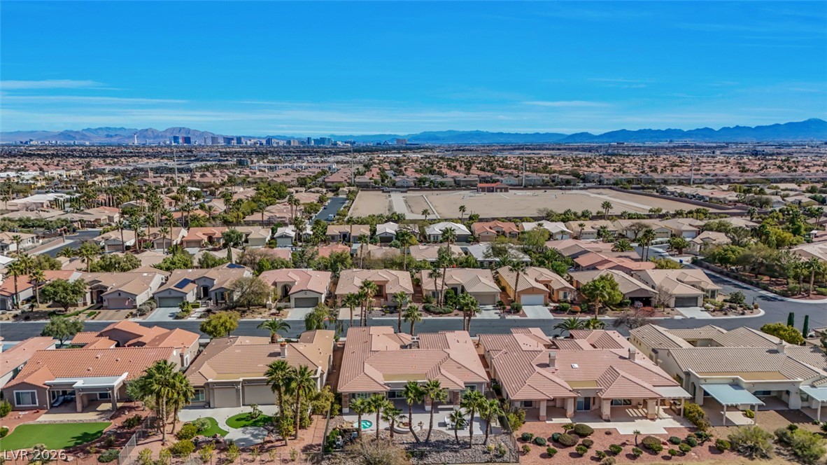 5015 Rivedro Street Las Vegas, NV 89135 - Photo 78 of 91 An aerial panorama showcases a desert community with terracotta roofs, verdant landscaping, and distant cityscapes framed by mountains.