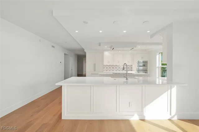 a living room with stainless steel appliances furniture a rug and a large window