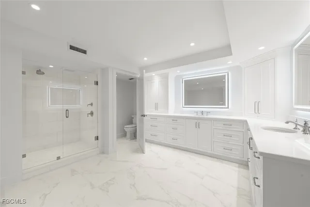 a spacious bathroom with double vanity sink a mirror and a toilet