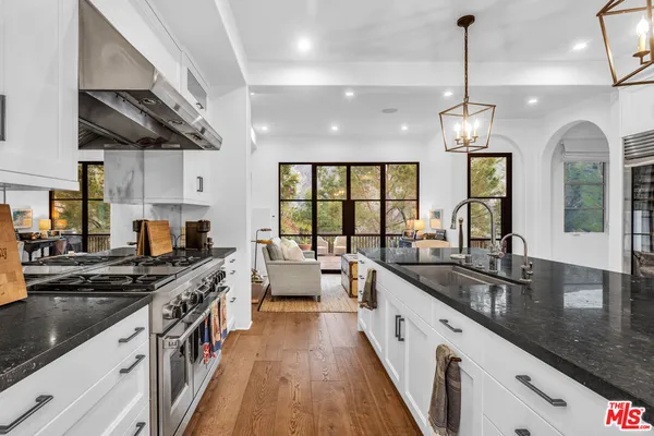 a large kitchen with stainless steel appliances granite countertop a stove a sink dishwasher and a flat tv screen