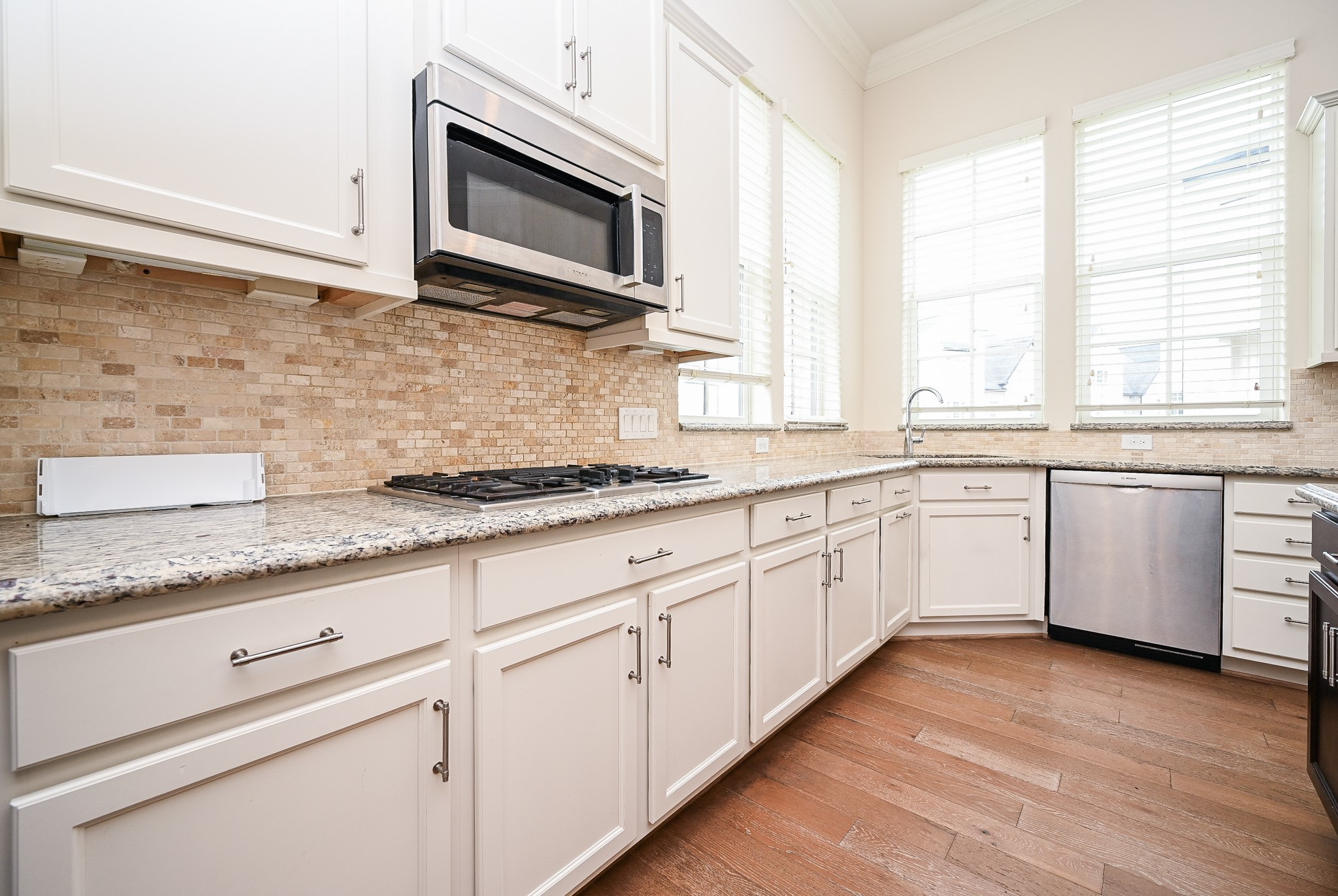 9546 London Bridge Station Houston, TX 77045 - Photo 18 of 41 Spacious, unobstructed pathways are highlighted by creamy granite countertops, a contrasting mosaic tile backsplash, and large windows that illuminate your tasks in this remarkable city kitchen.