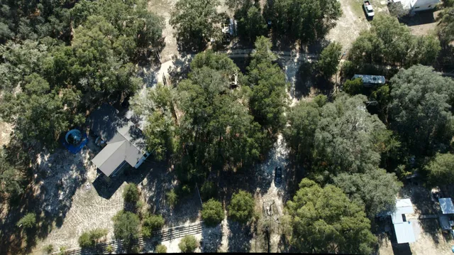 an aerial view of residential house with outdoor space and trees all around