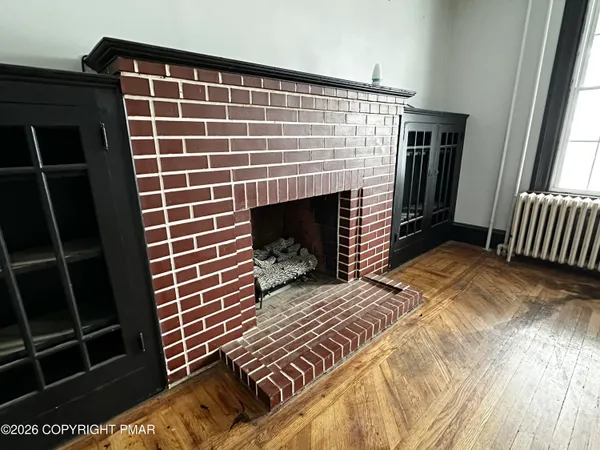 a view of an empty room with wooden floor and a fireplace