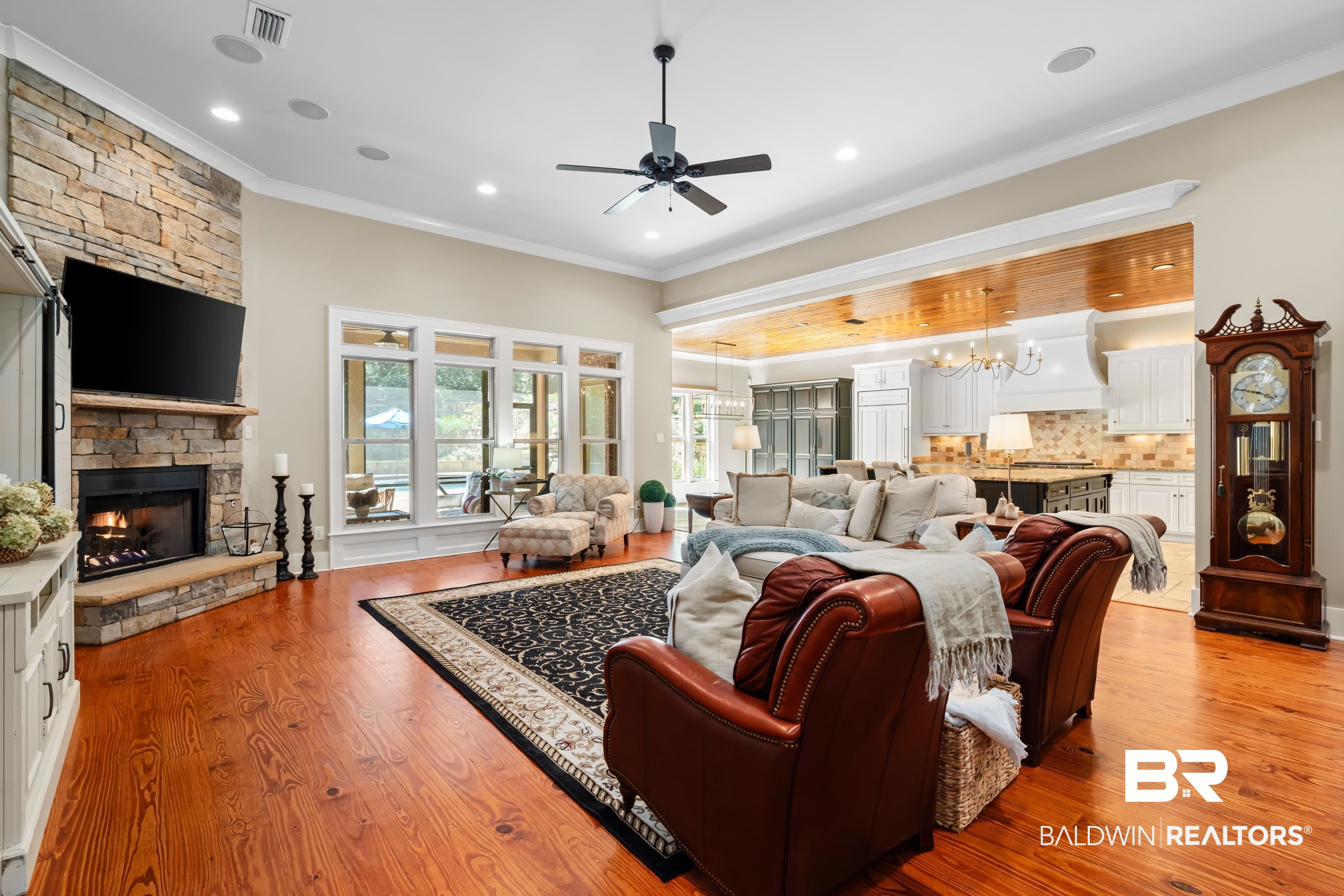 30057 Dolive Ridge Daphne, AL 36527 - Photo 10 of 55 Living room with a stone fireplace, ceiling fan with notable chandelier, crown molding, and light hardwood / wood-style floors