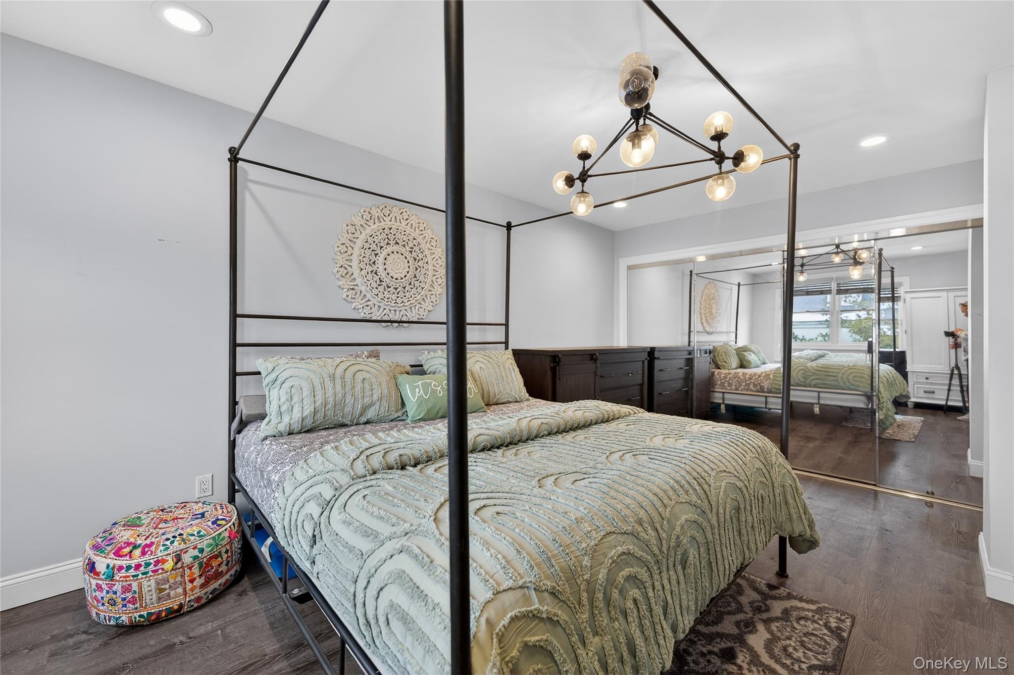 3530 Long Beach Road, Unit 8 Oceanside, NY 11572 - Photo 10 of 19 a bedroom with a bed mirror and clock on wall