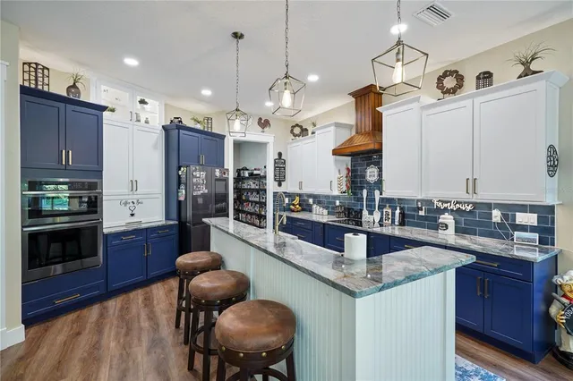a kitchen with stainless steel appliances granite countertop a sink dishwasher a refrigerator and wooden cabinets with wooden floor