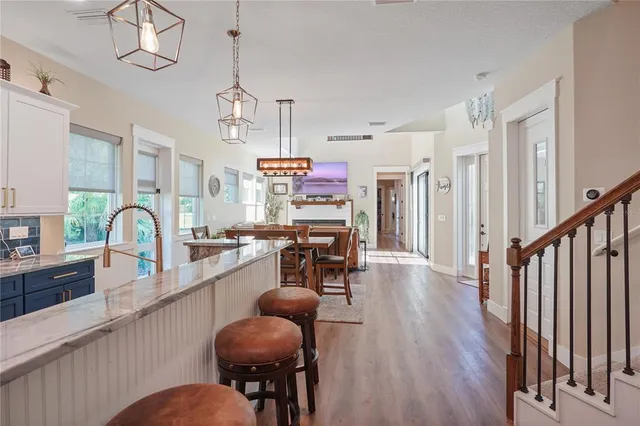 a view of a dining room and livingroom with furniture wooden floor a chandelier