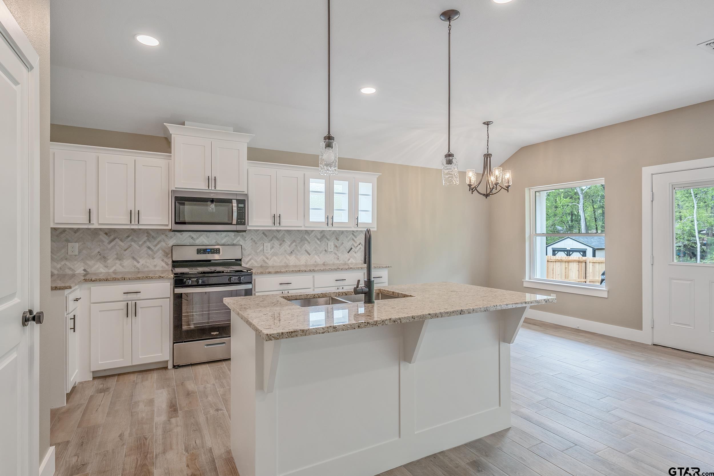 16218 Crossing Circle Lindale, TX 75771 - Photo 5 of 24 a kitchen with stainless steel appliances granite countertop a sink a stove a refrigerator and white cabinets with wooden floor
