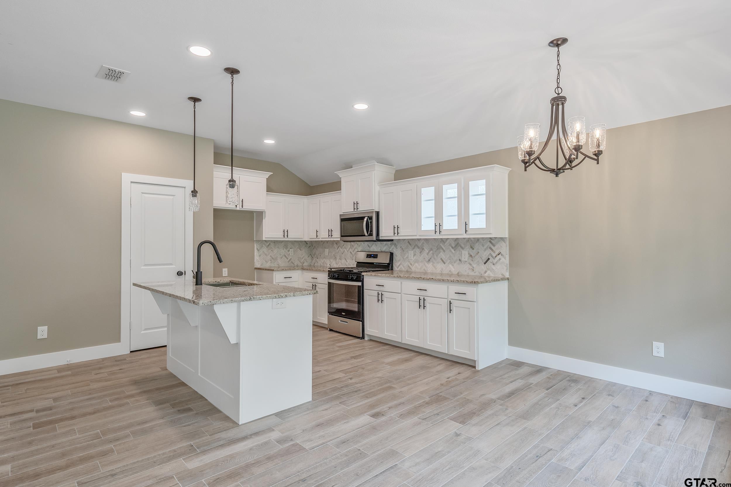 16218 Crossing Circle Lindale, TX 75771 - Photo 8 of 24 a kitchen with stainless steel appliances granite countertop a sink a stove a refrigerator and white cabinets with wooden floor