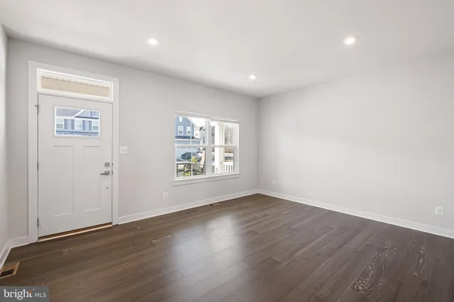 an empty room with wooden floor and window