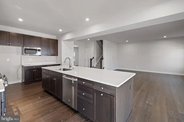 a kitchen with a sink a stove cabinets and wooden floor