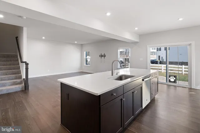 a kitchen with a stove a sink a refrigerator and wooden floor