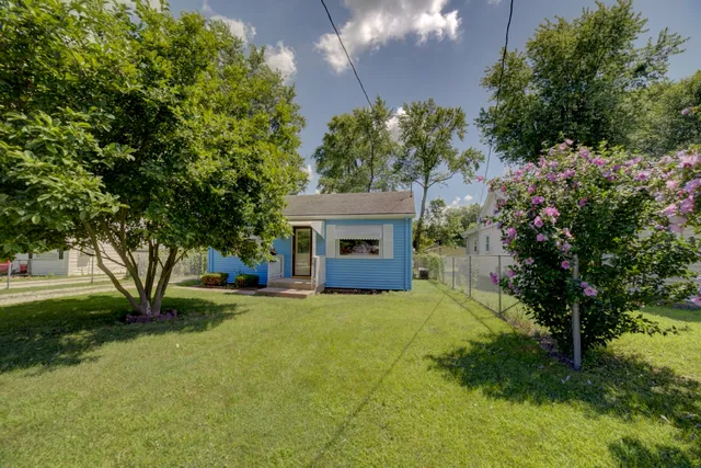 a front view of a house with a garden and trees
