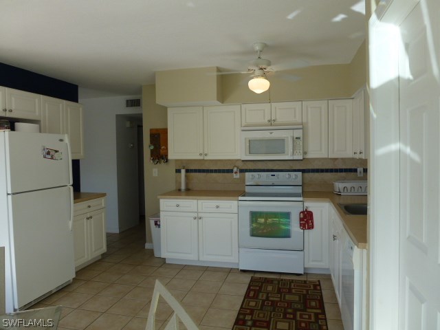 1450 Mandel Road Fort Myers, FL 33919 - Photo 13 of 18 a kitchen with a refrigerator and white cabinets