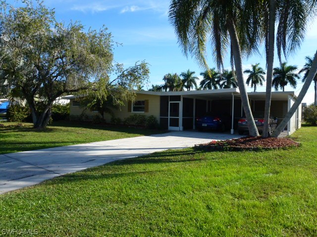 1450 Mandel Road Fort Myers, FL 33919 - Photo 2 of 18 a view of a house with a yard and palm trees
