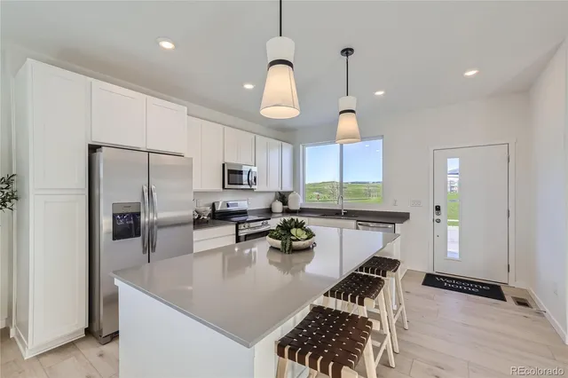 a kitchen with a refrigerator a stove a sink dishwasher a dining table and chairs with wooden floor