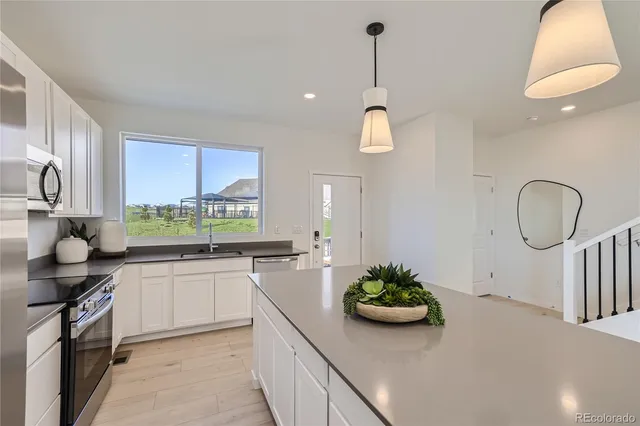 a kitchen with kitchen island stainless steel appliances a sink a stove and a wooden floors