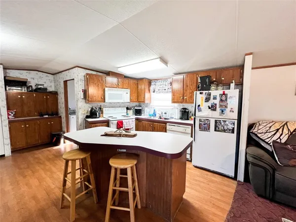 a kitchen with stainless steel appliances a sink a stove a refrigerator cabinets and a dining table with wooden floor