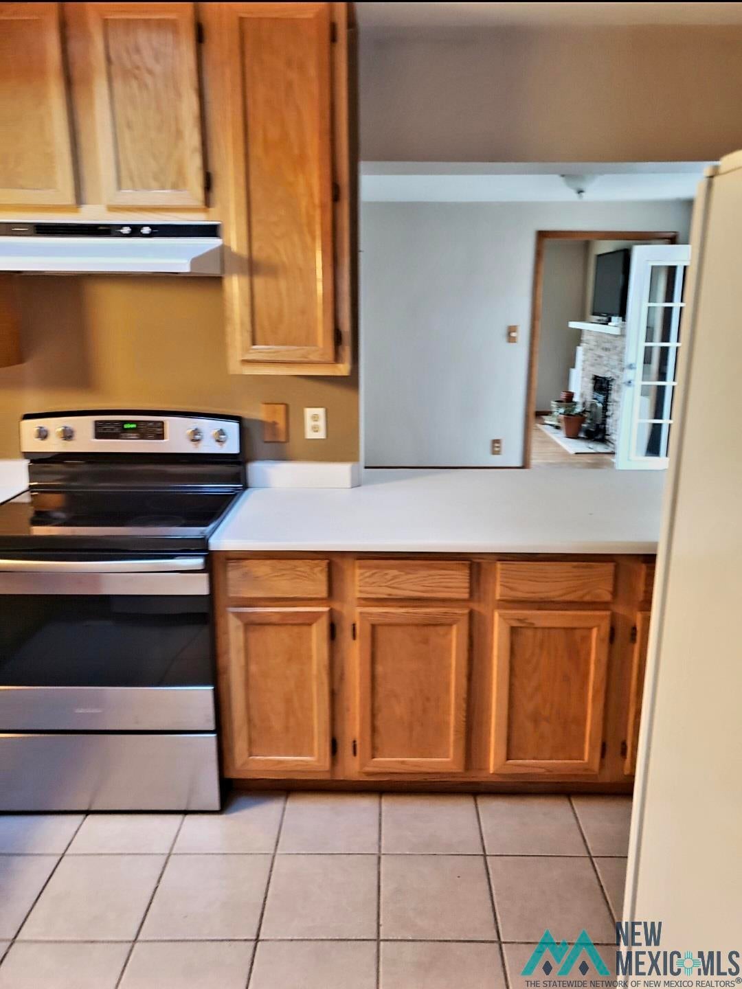 1375 Brilliant Street Raton, NM 87740 - Photo 9 of 19 Kitchen featuring stainless steel electric stove, light countertops, light tile patterned floors, and wood finish cabinetry