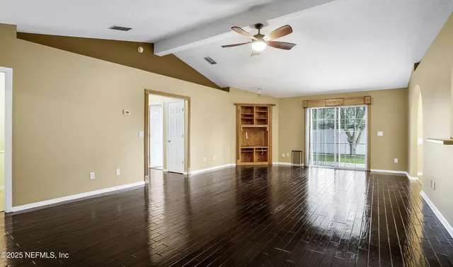 a view of an empty room with wooden floor and a window
