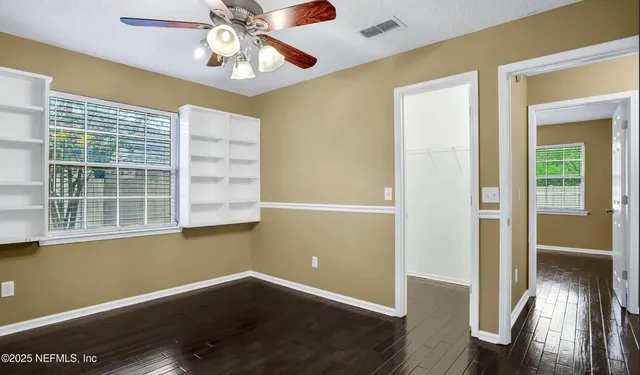 an empty room with wooden floor cabinet and windows