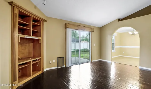 a view of empty room with wooden floor and windows