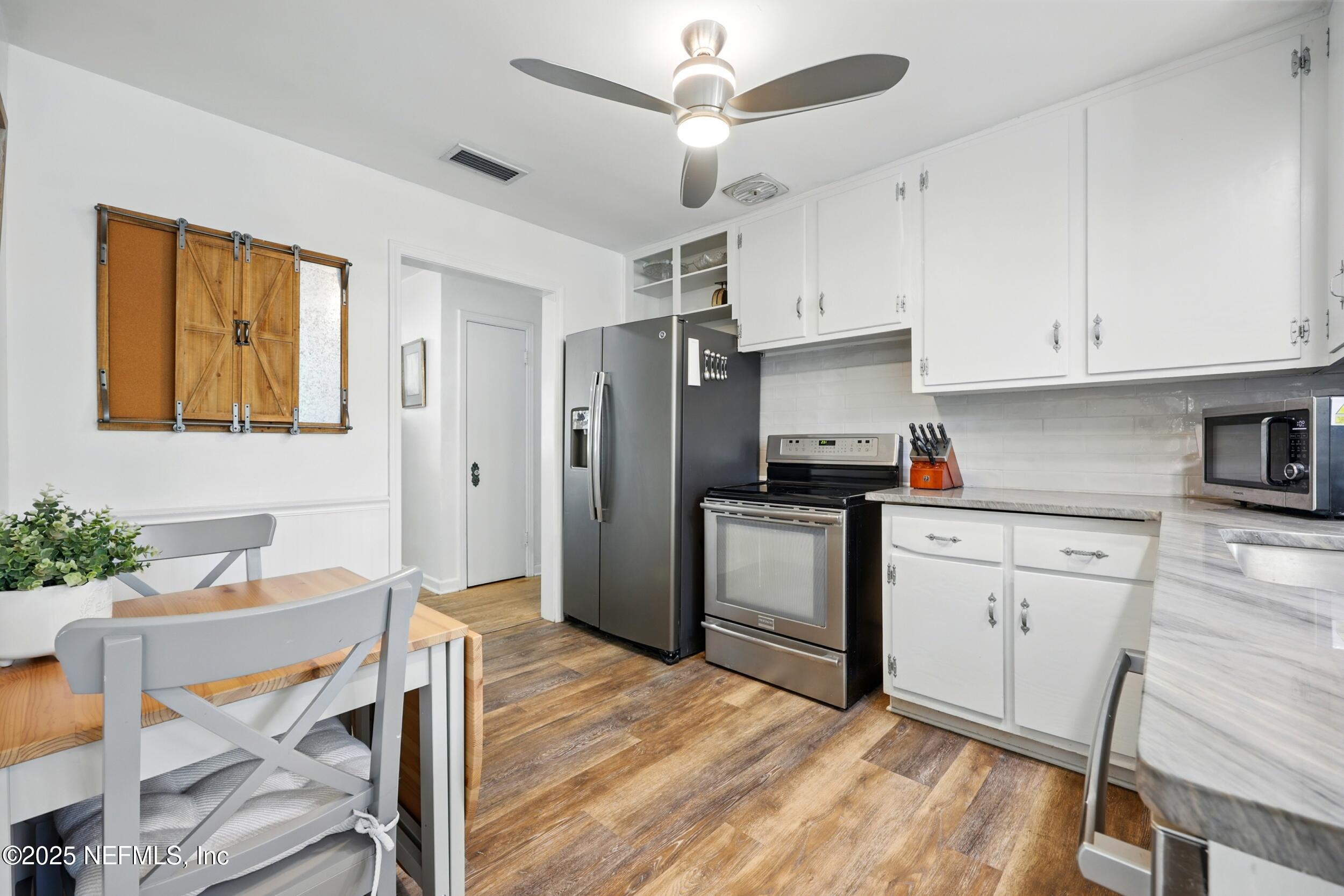 6414 Colgate Road Jacksonville, FL 32217 - Photo 10 of 33 a kitchen with stainless steel appliances granite countertop a refrigerator a stove a sink dishwasher and white cabinets with wooden floor