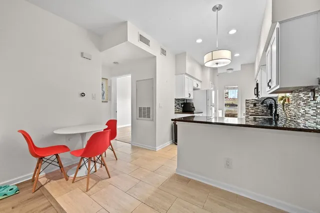 a kitchen with stainless steel appliances kitchen island granite countertop a table chairs in it and wooden floors