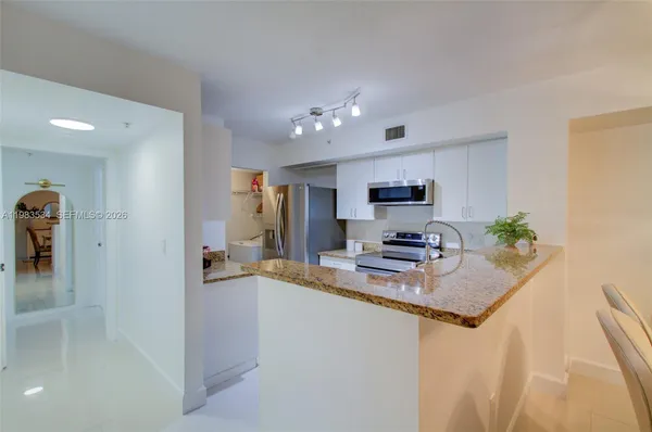 a kitchen with granite countertop a sink a stove and cabinets