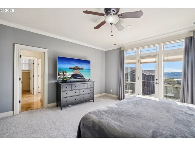 a bedroom with a bed and a large window with a fan