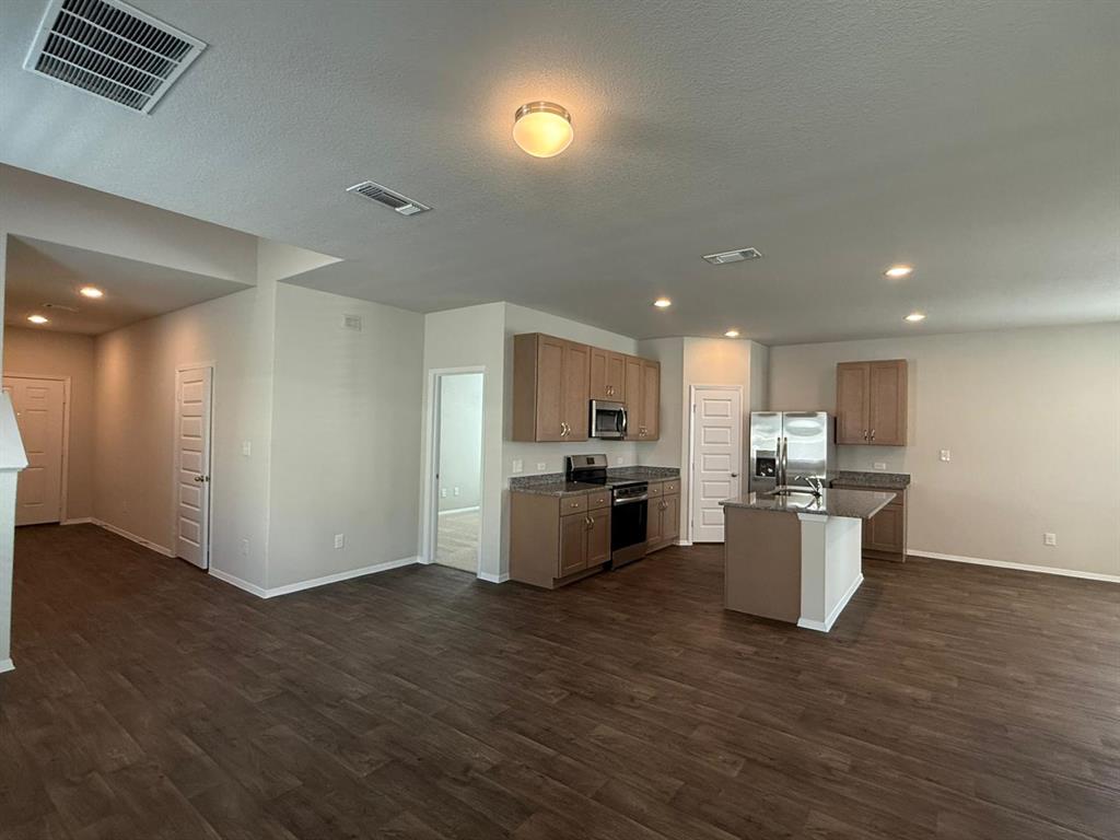 2707 Totley Road Manor, TX 78653 - Photo 38 of 39 Kitchen with a kitchen island with sink, stainless steel appliances, dark wood-style flooring, open floor plan, and a textured ceiling