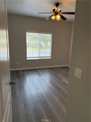 an empty room with wooden floor and a ceiling fan