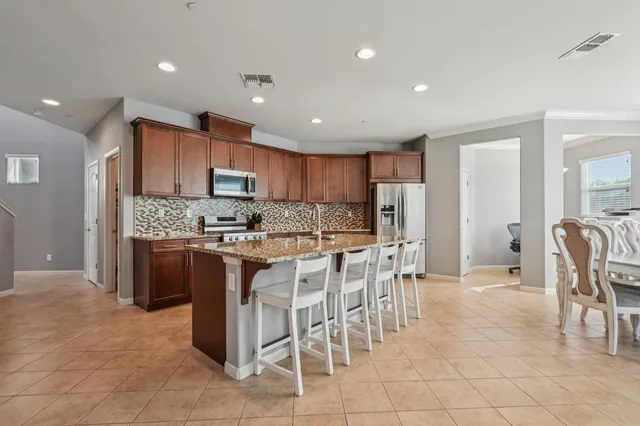 a kitchen with stainless steel appliances kitchen island granite countertop a refrigerator and a stove top oven