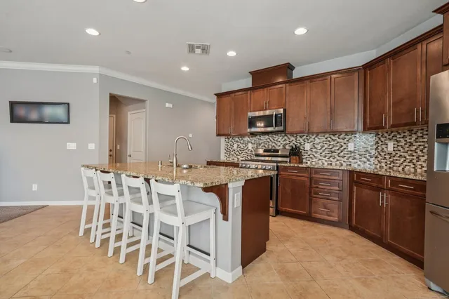 a kitchen with stainless steel appliances granite countertop wooden cabinets a stove top oven a sink and dishwasher