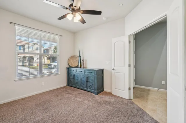 a view of an empty room with chandelier fan and a window