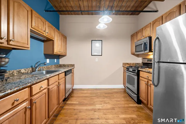 a kitchen with stainless steel appliances granite countertop a refrigerator a stove and a sink