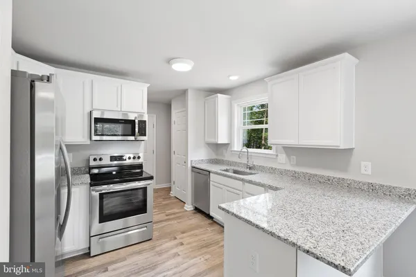 a large kitchen with granite countertop a sink stainless steel appliances and cabinets