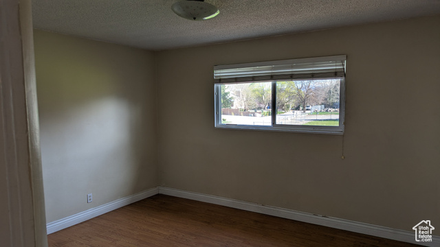 1341 East Crk Road Sandy, UT 84093 - Photo 16 of 24 Empty room featuring wood finished floors, baseboards, and a textured ceiling