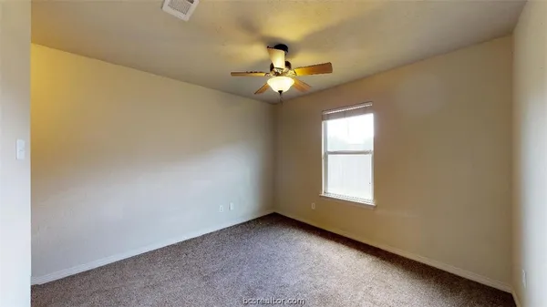 an empty room with windows and fan