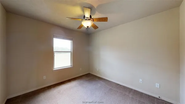 an empty room with windows and chandelier fan