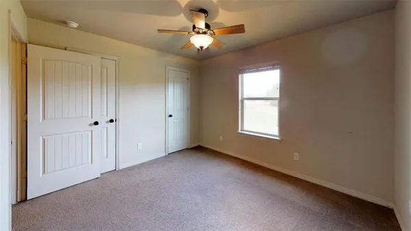 an empty room with a window and a fan