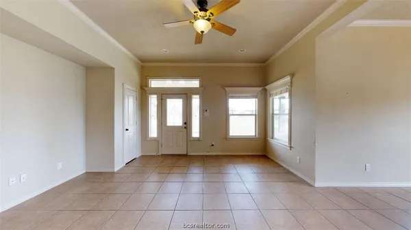 a view of an empty room with window and chandelier fan