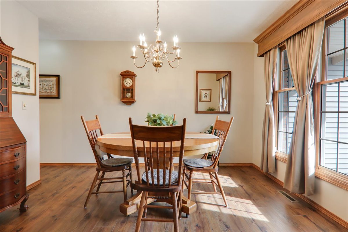 8 Minks Court Bloomington, IL 61704 - Photo 15 of 40 a dining room with furniture wooden floor a rug a potted plant a painting and a chandelier