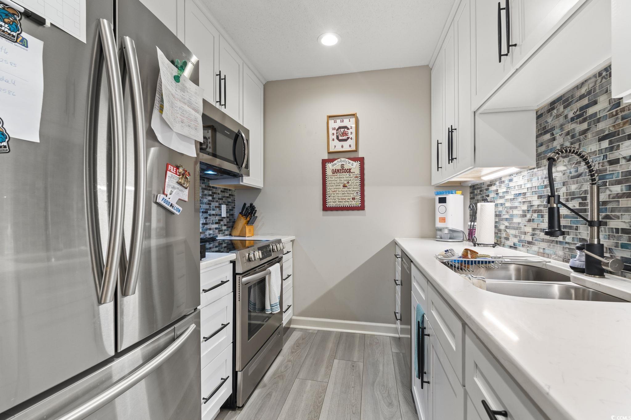 5001 Little River Road, Unit W102 Myrtle Beach, SC 29577 - Photo 9 of 38 Kitchen featuring stainless steel appliances, light wood-type flooring, light countertops, white cabinetry, and recessed lighting