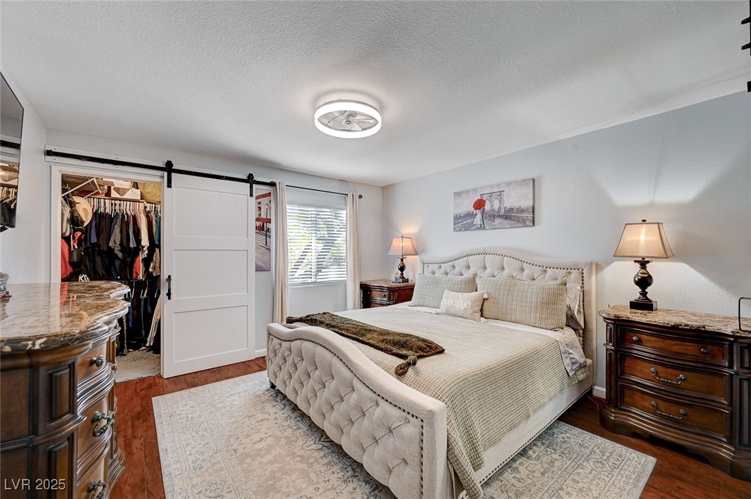 7885 West Flamingo Road, Unit 2023 Las Vegas, NV 89147 - Photo 14 of 34 Bedroom featuring a barn door, wood finished floors, a walk in closet, a textured ceiling, and a closet