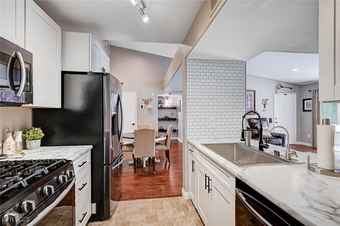 7885 West Flamingo Road, Unit 2023 Las Vegas, NV 89147 - Photo 6 of 34 Kitchen with appliances with stainless steel finishes, a sink, white cabinets, and decorative backsplash